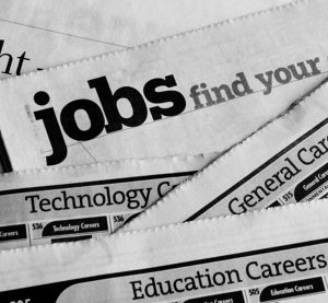 Newspaper job listing pages, stacked to illustrate job search and employment opportunities and the job hunting process of looking for careers and occupations in the classified ad section of printed papers. For concepts of unemployment, employment issues, recession, economic depression, recovery, technology and education careers. Vertical image with copy space.